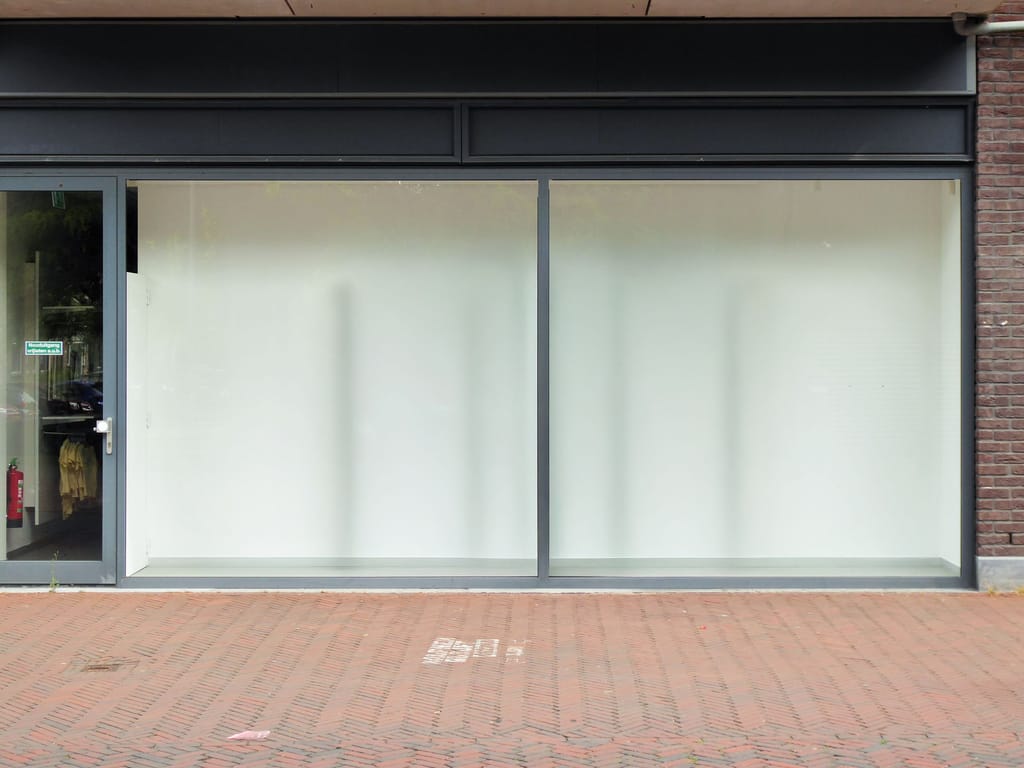 An empty ground-floor showroom, glass frontage, waiting for a tenant.