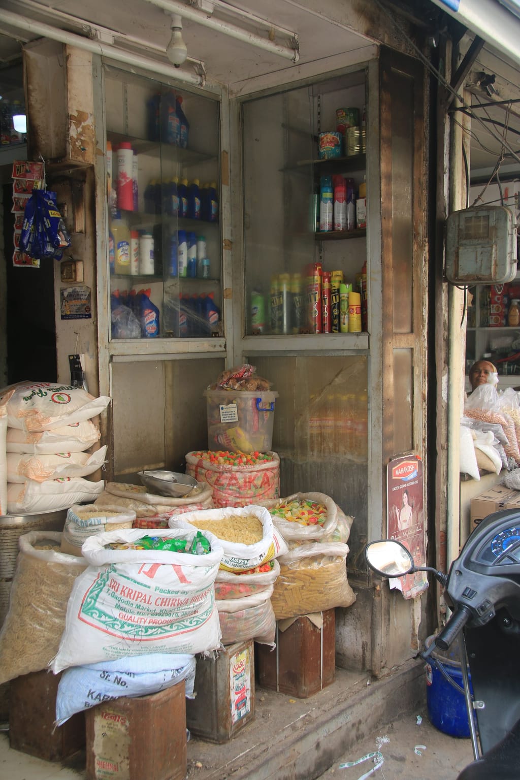 A neighbourhood grocery shop with sacks of grain stacked out front.