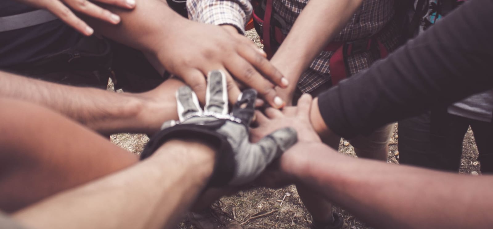 Many hands brought together over one place, everyone reaching in.