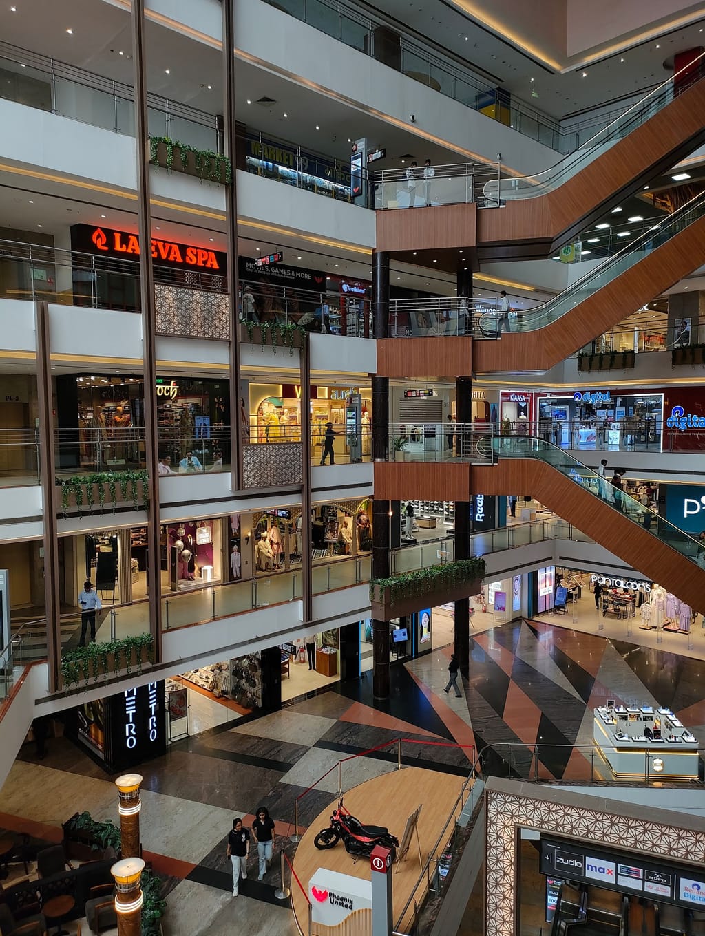 The inside of an Indian shopping mall, shopfronts rising on either side.