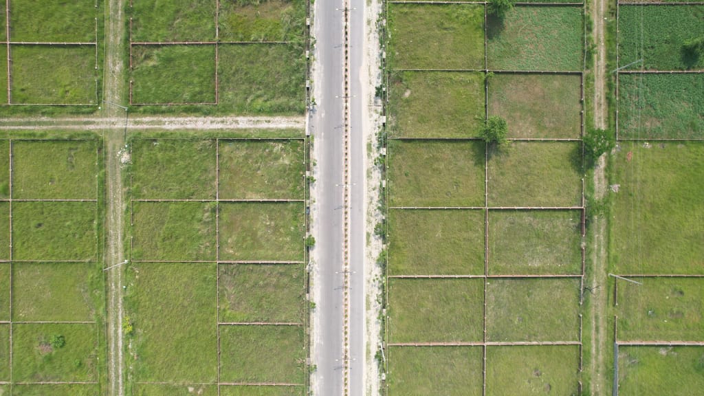 A road running between green fields, the land before anything is built on it.