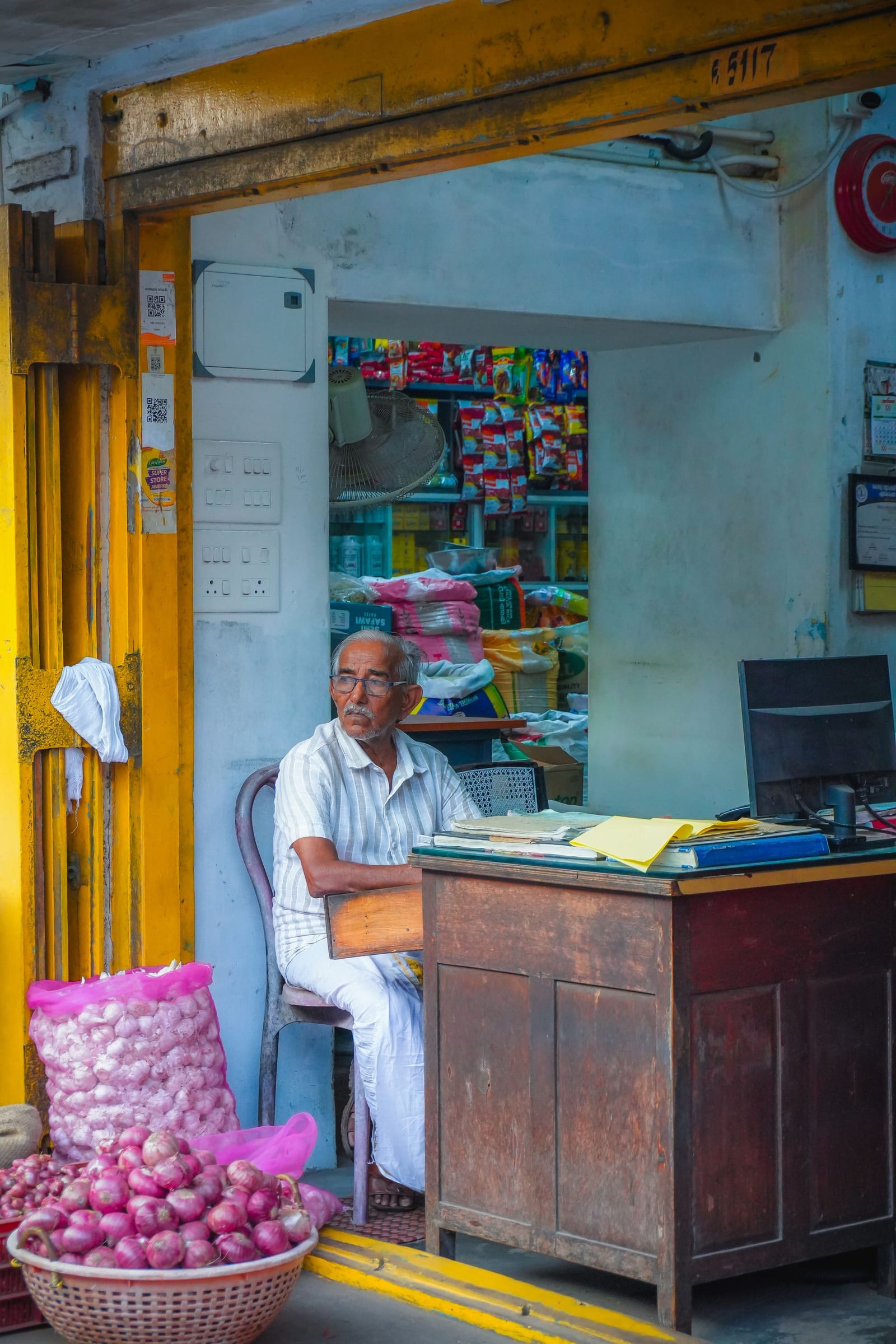A shopkeeper at his desk in a small grocery store.